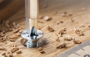 Csavarhúzóval csavart csavar egy tölgyfa deszkában.