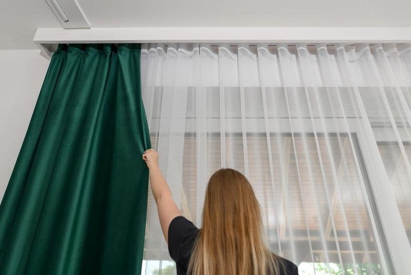 Függönyrúdon lógó vastag zöld függöny.
