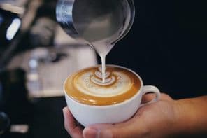 Barista tejet önt egy kávésbögrébe.