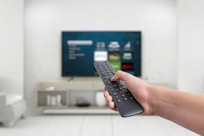 Kézben egy okos tévé távirányítója, amely alkalmazásgombokkal rendelkezik.