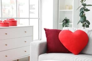 Hangulatos szürke kanapé szív alakú párnával a nappaliban.