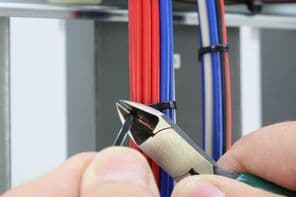 A kábelkötegelő elvágása a szigetelt rögzítő vezetéken az elektromos panelben.